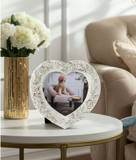 Distress white heart picture frame with a photo of a dog on a side table in a living room.