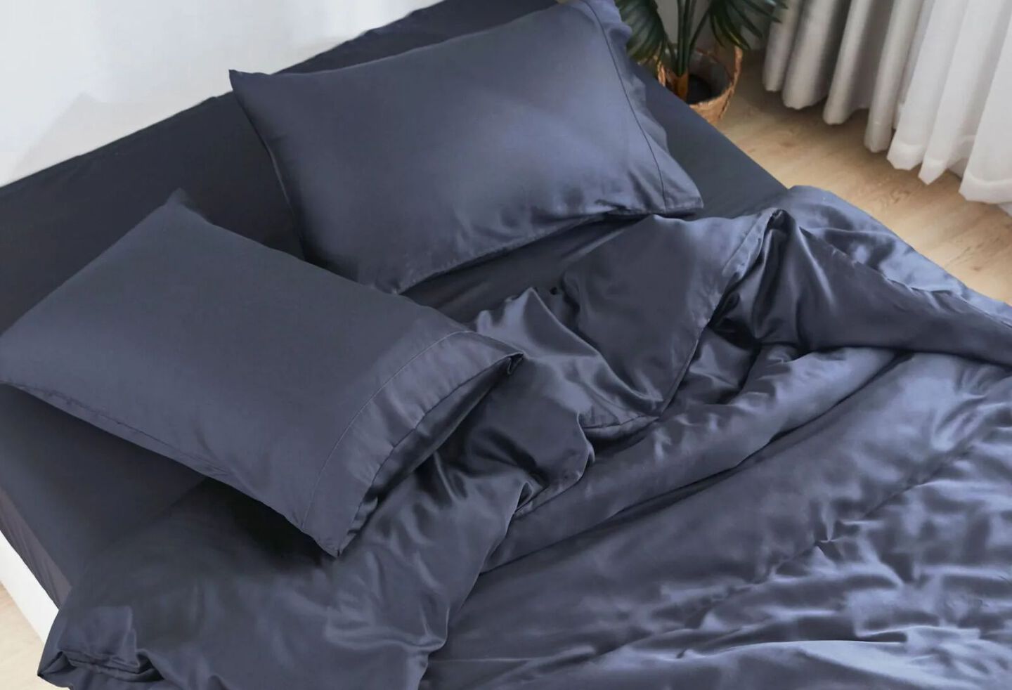 Unmade bed with navy blue sheets and matching pillows