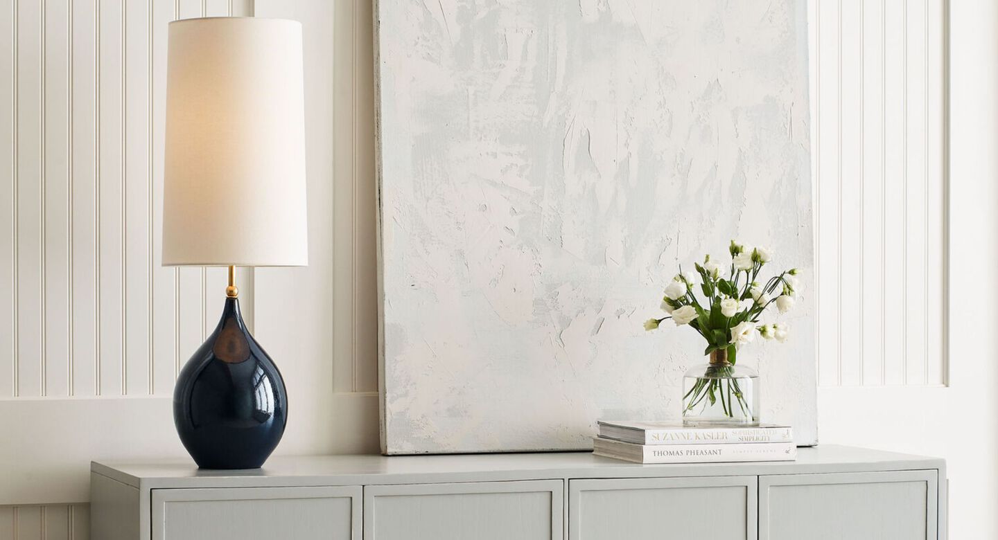 Navy lamp with a white lampshade sitting on top of a light grey cabinet