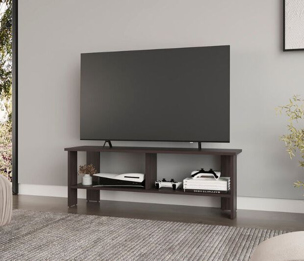 Flat screen TV sitting on a basic brown TV stand with a divided shelf with a gaming console and decor items under the television.