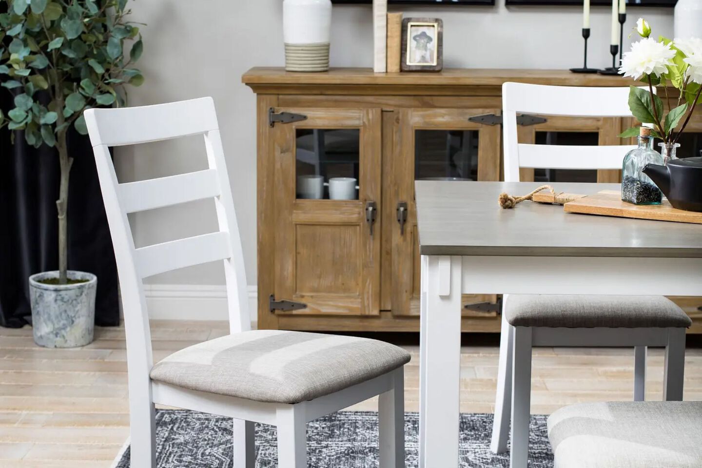 Kitchen with grey and white dining table, matching chairs, and a wooden buffet
