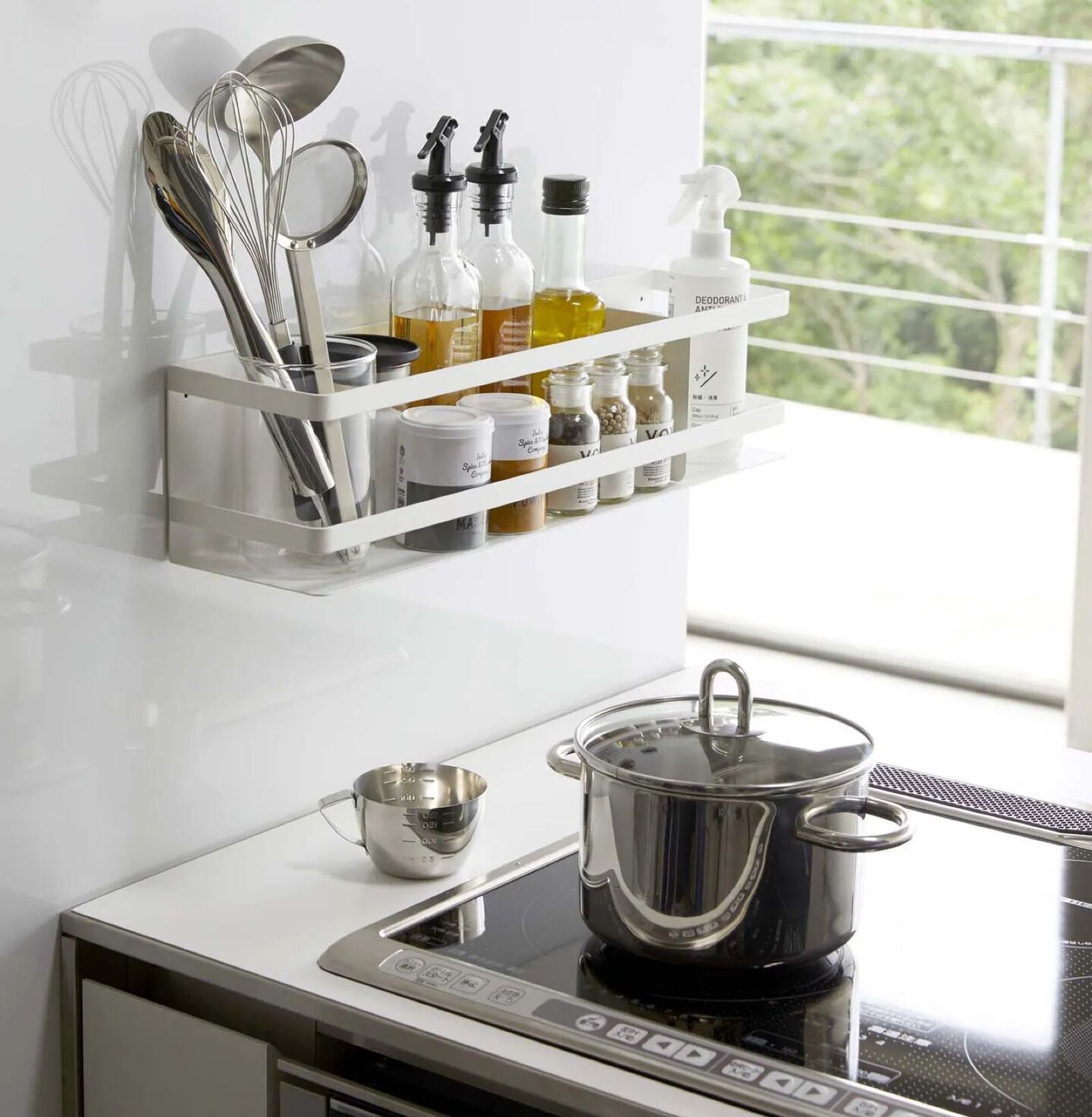 Kitchen with white shelf filled with cooking utensils and oils and a stovetop with a pot on top