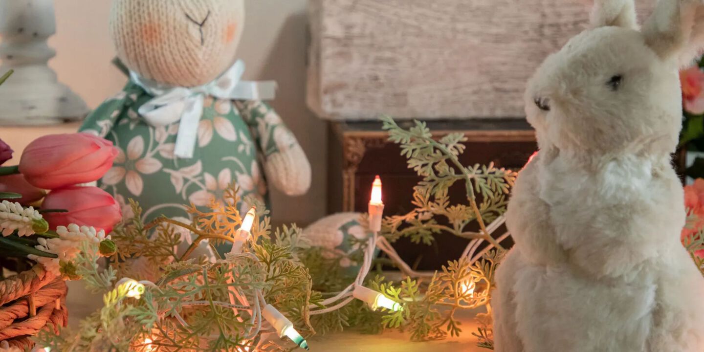 Table with two plush bunnies and a garland with pastel colored lights intertwined within it