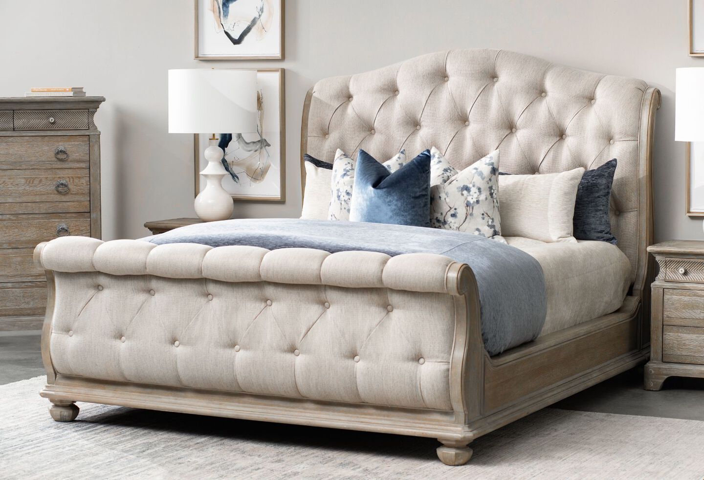 Light grey upholstered sleigh bed with blue and white pillows on top