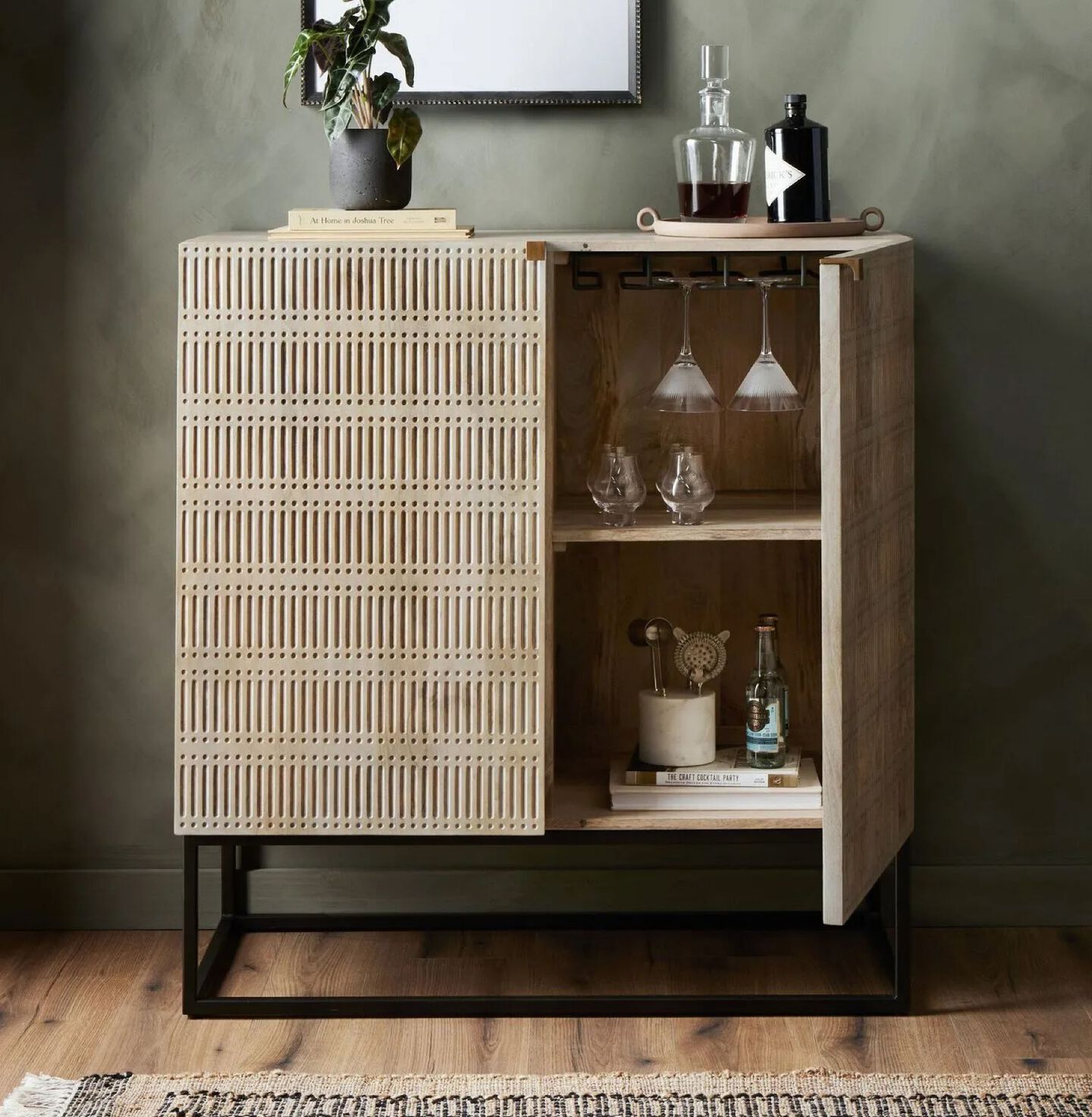 Light brown wooden cabinet with black hardware and one open door