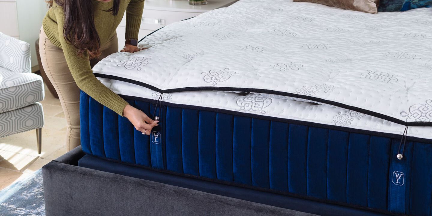 Person securing the top cover of a navy and white mattress