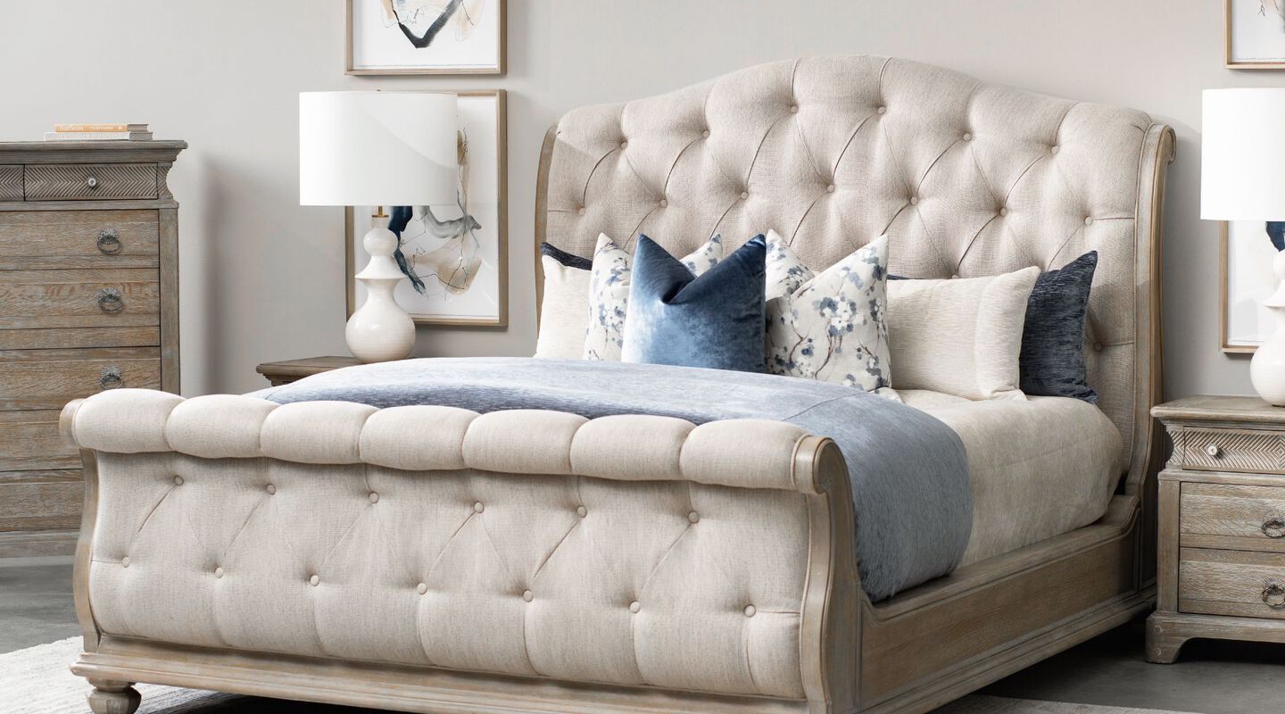 Beige upholstered sleigh bed with blue and beige pillows atop
