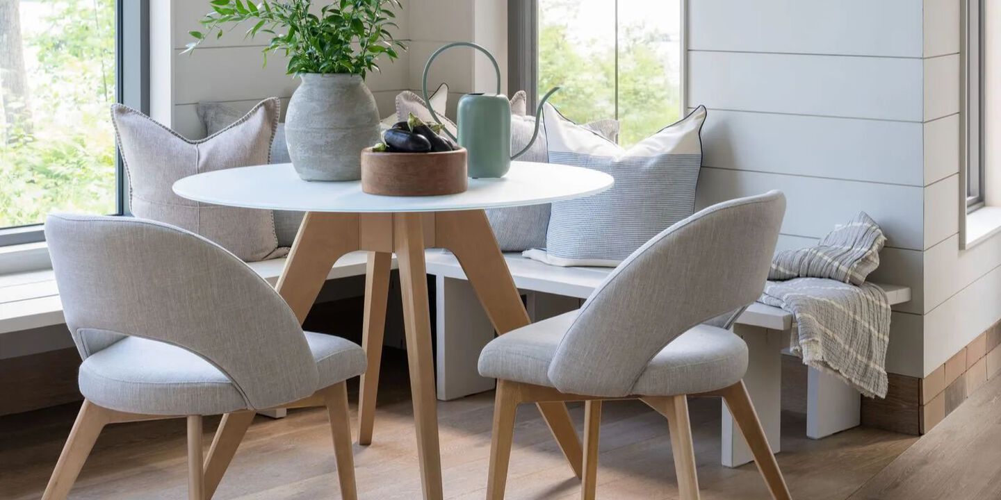 Dining room set with white table with wooden legs and two grey upholstered chairs with wooden legs