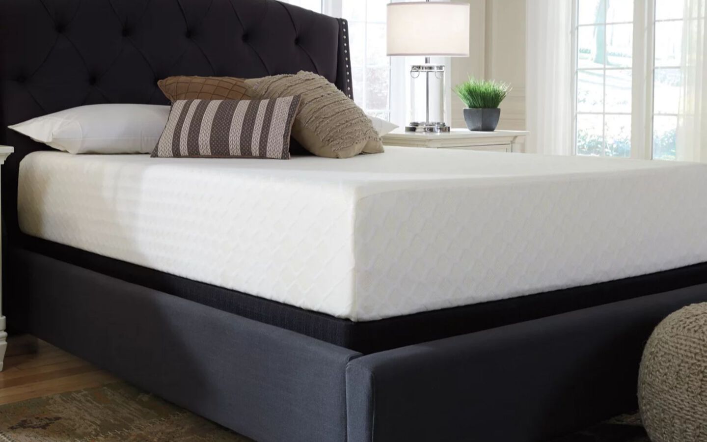 Closeup image of the corner of a white mattress atop a dark grey bedframe