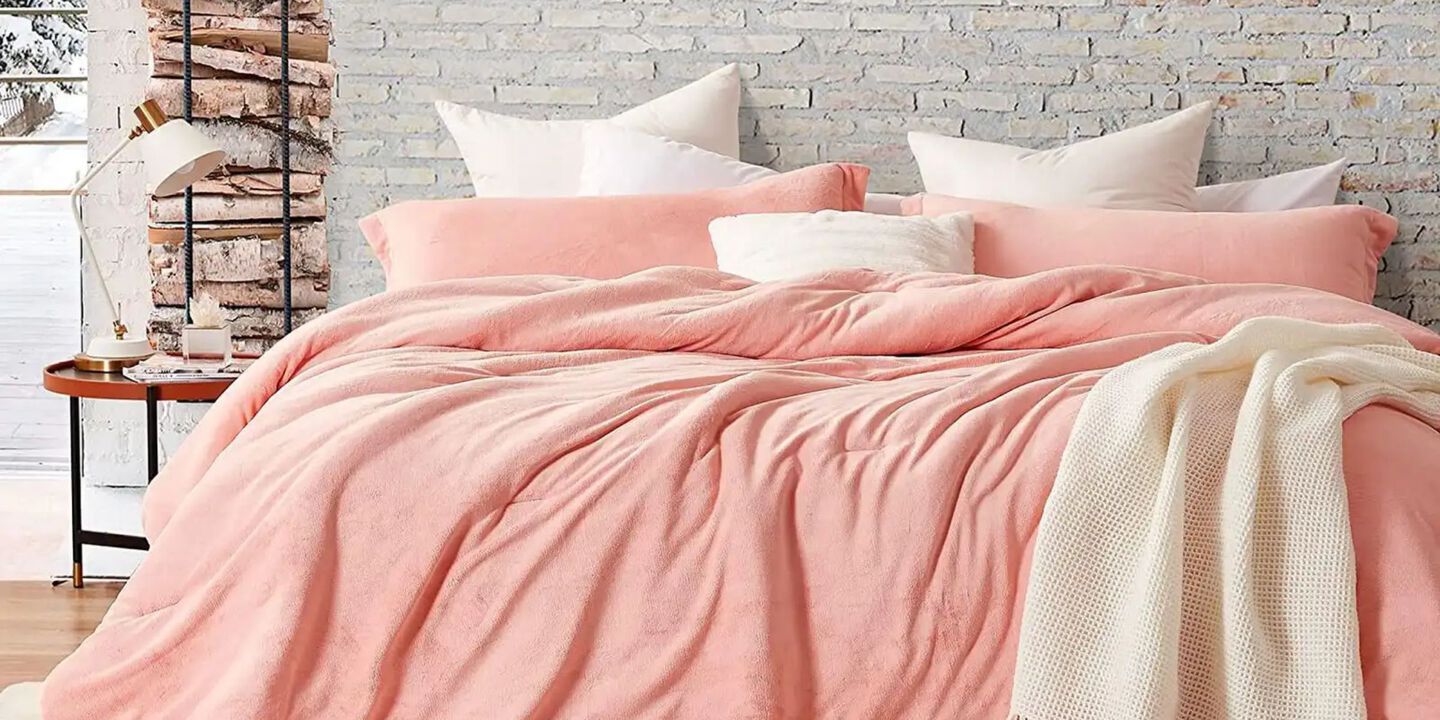 Bed covered in a plush peach-colored comforter and peach and white pillows