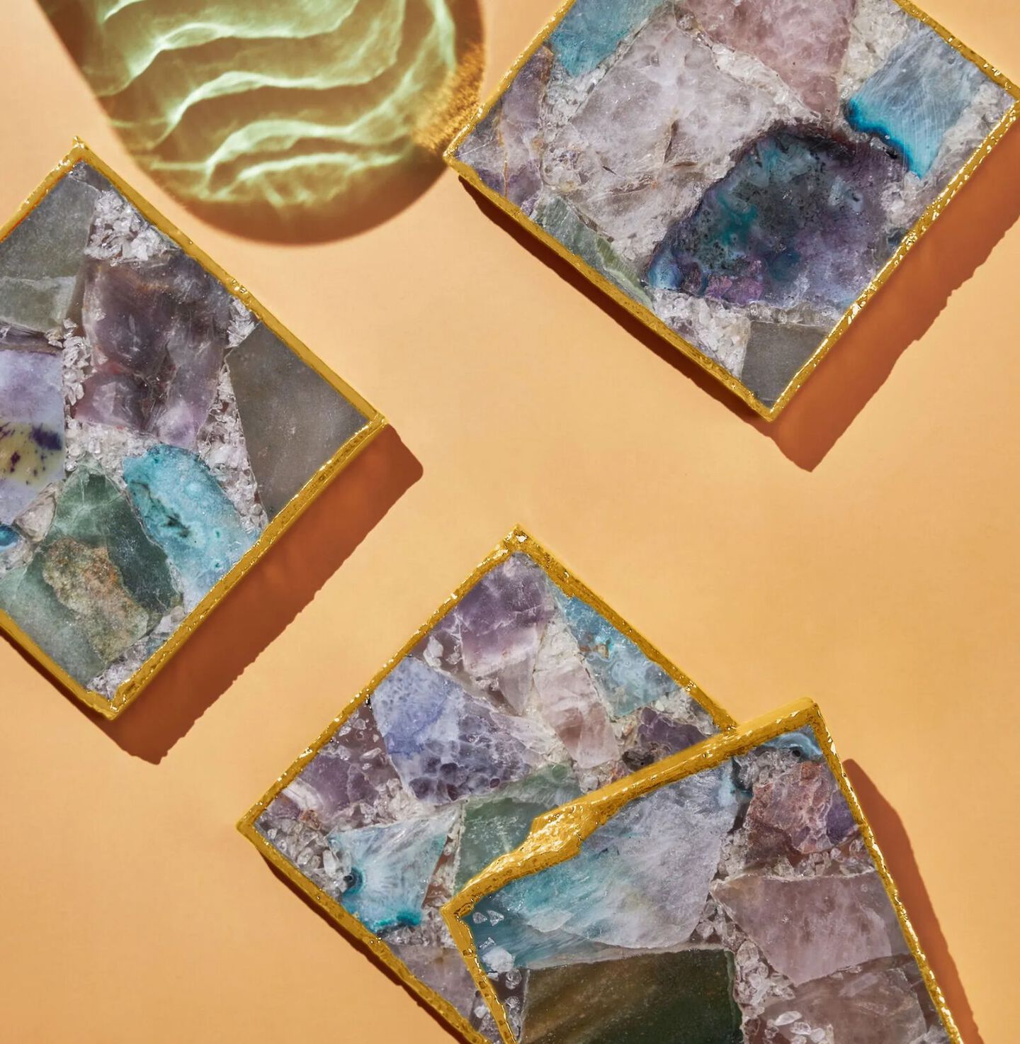 Peach colored table with four blue and purple geode coasters with gold trim