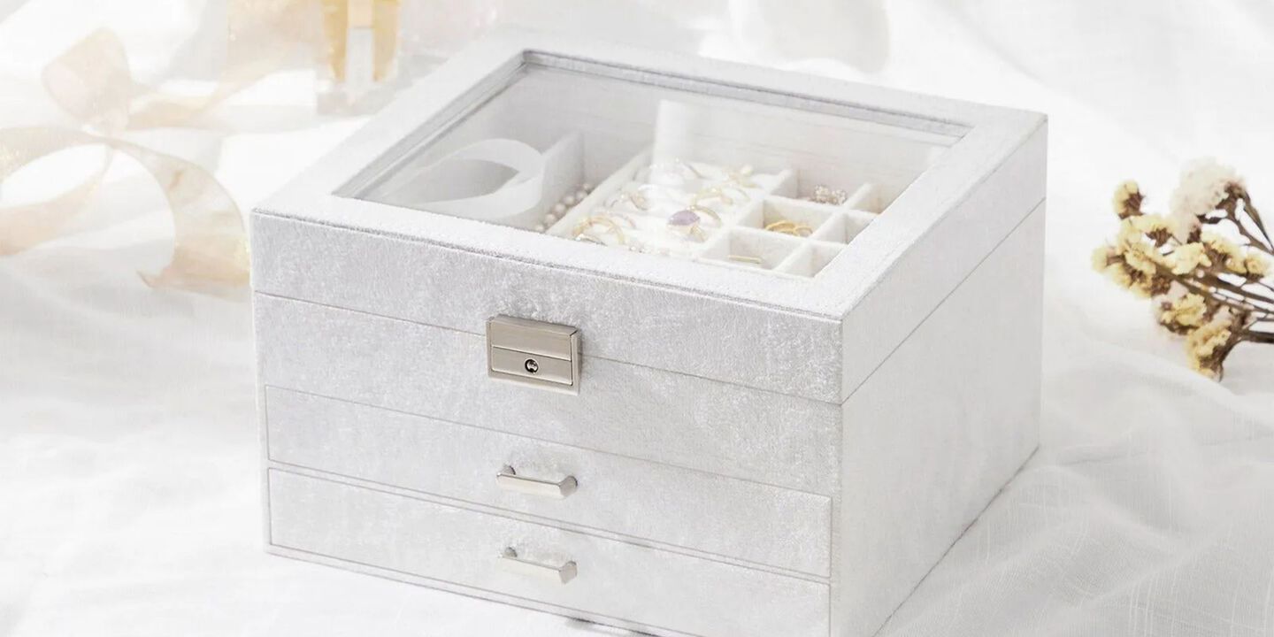 A white velvet jewelry box filled with various pieces of gold jewelry
