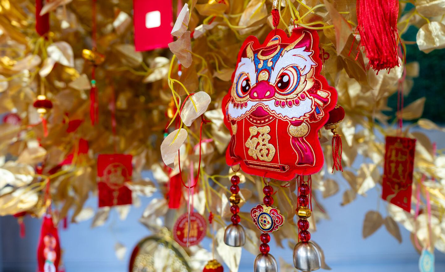 A red and yellow dragon ornament hanging in a golden tree