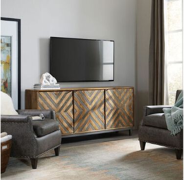 A modern median console with a geometric design with a TV just above the console.