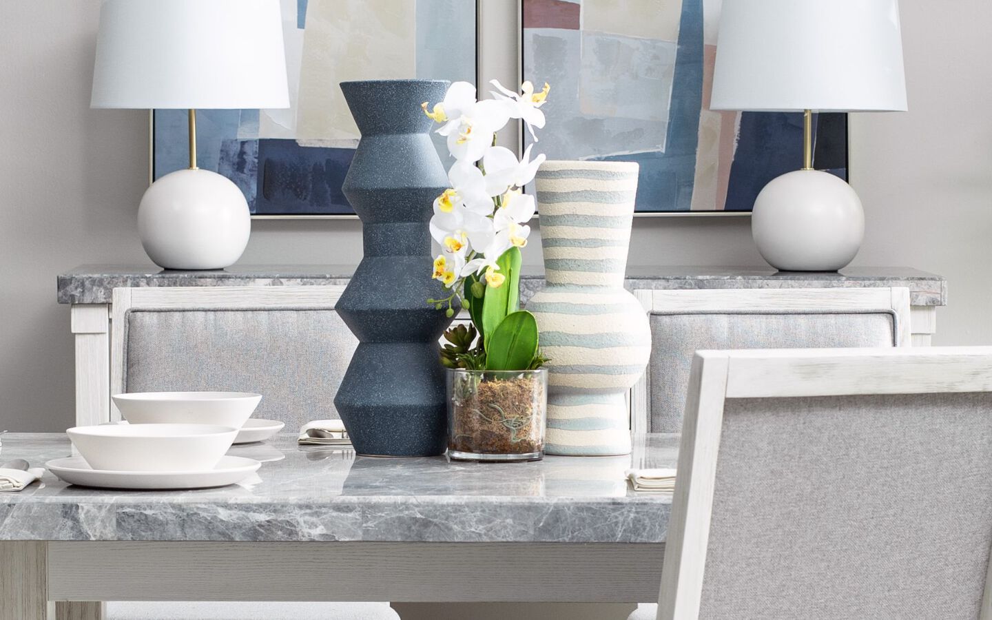 Grey marble dining table with three vases and faux plant sitting on top