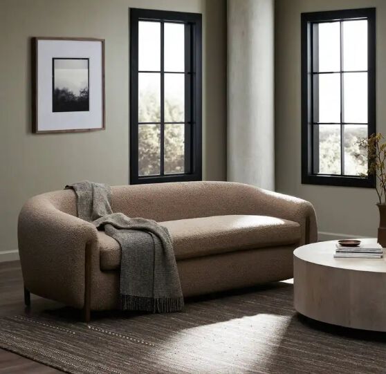 Modern beige curved sofa with throw blanket in minimalist living room