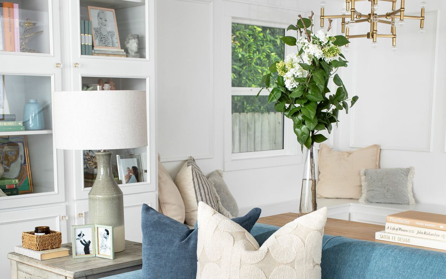 Living room with light wooden furniture, blue couch, and faux plant in a glass vase