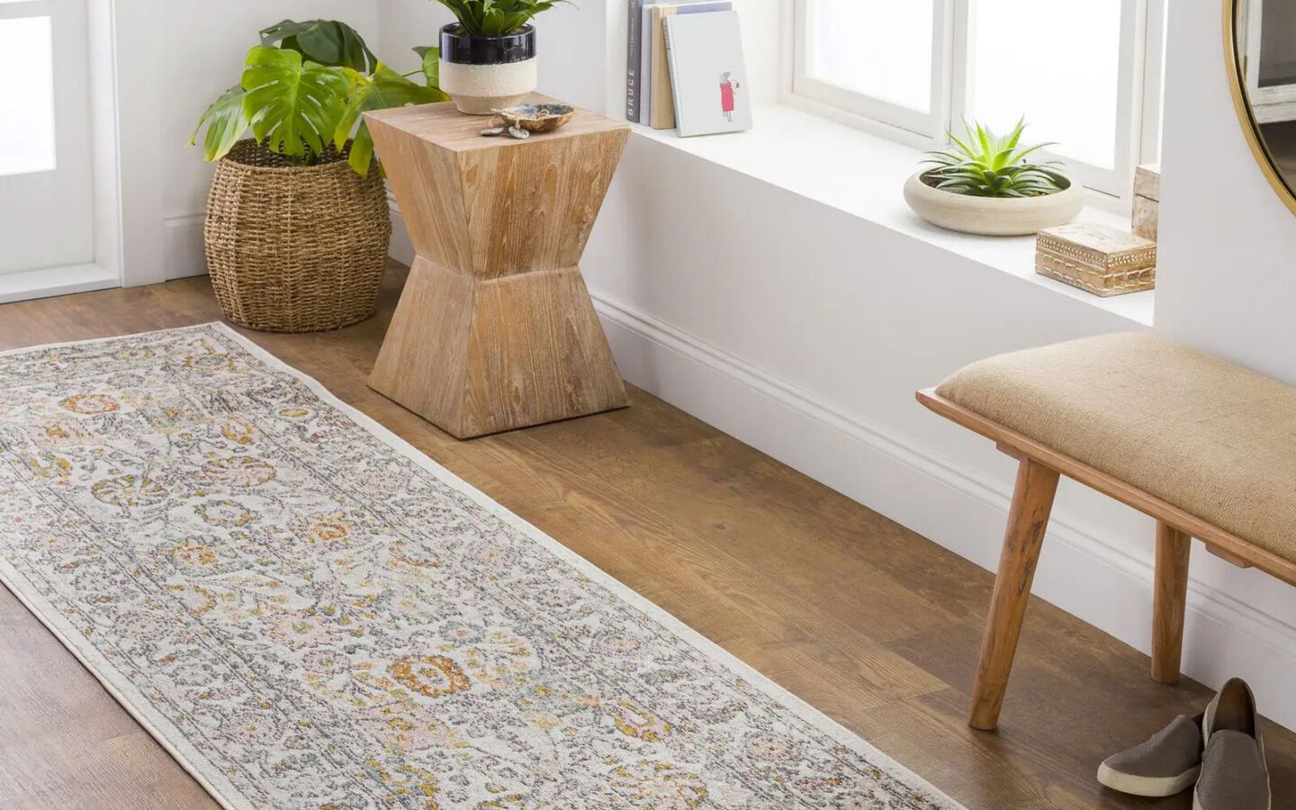 entryway with light beige runner rug, tan bench, and light wood side table