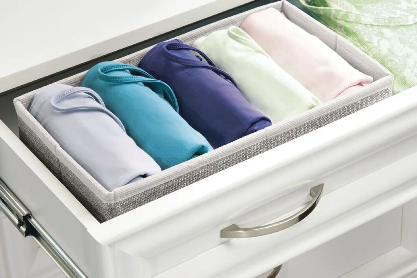 White open drawer with a grey basket inside filled with rolled clothing