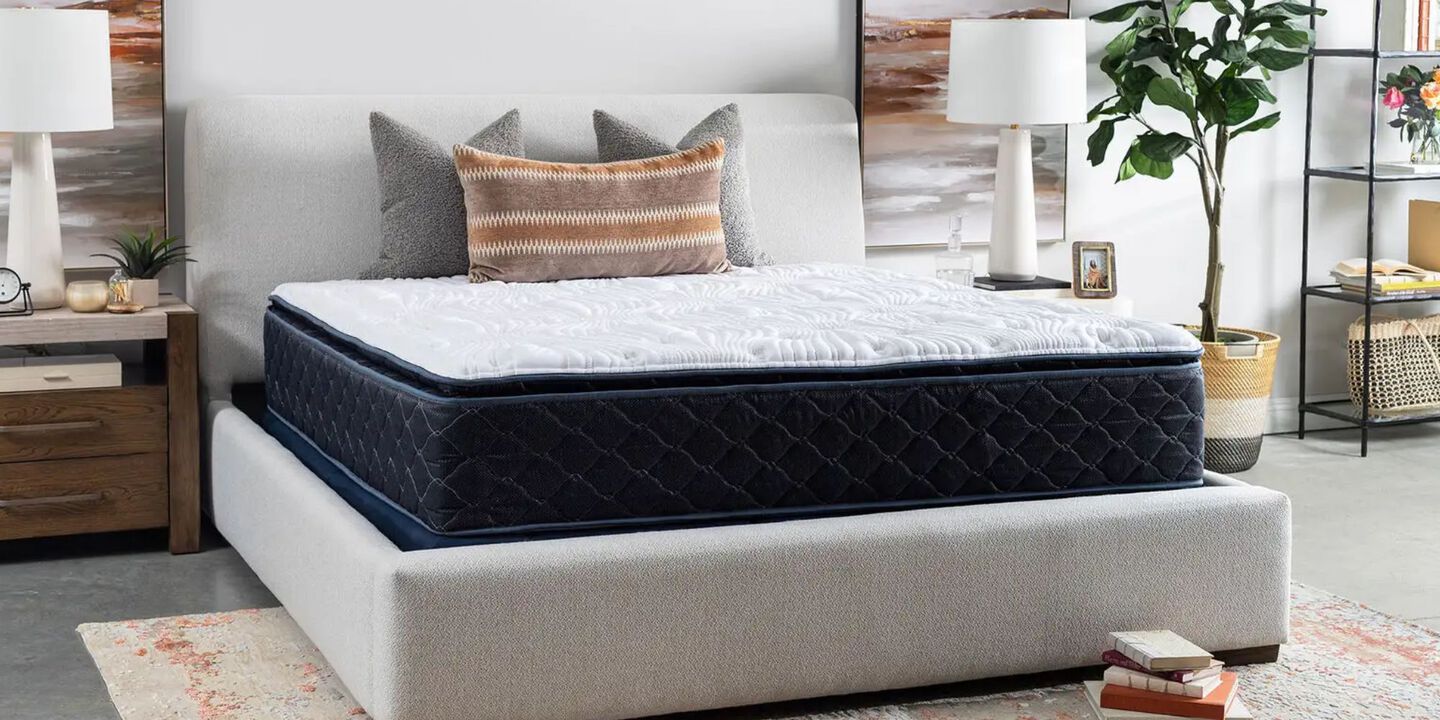 Mattress with three pillows on top sitting on a grey bedframe