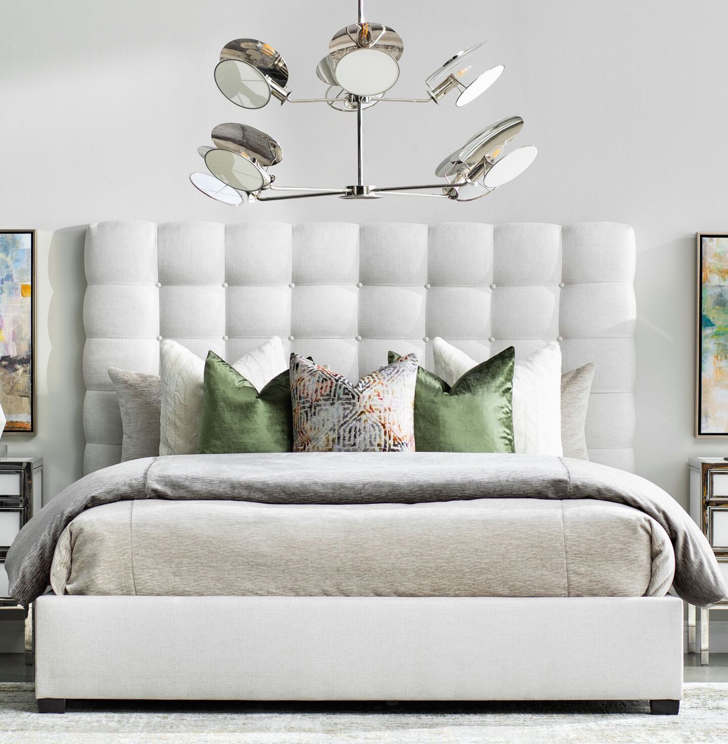 Unique light fixture hanging above a light grey bed with green assorted pillows