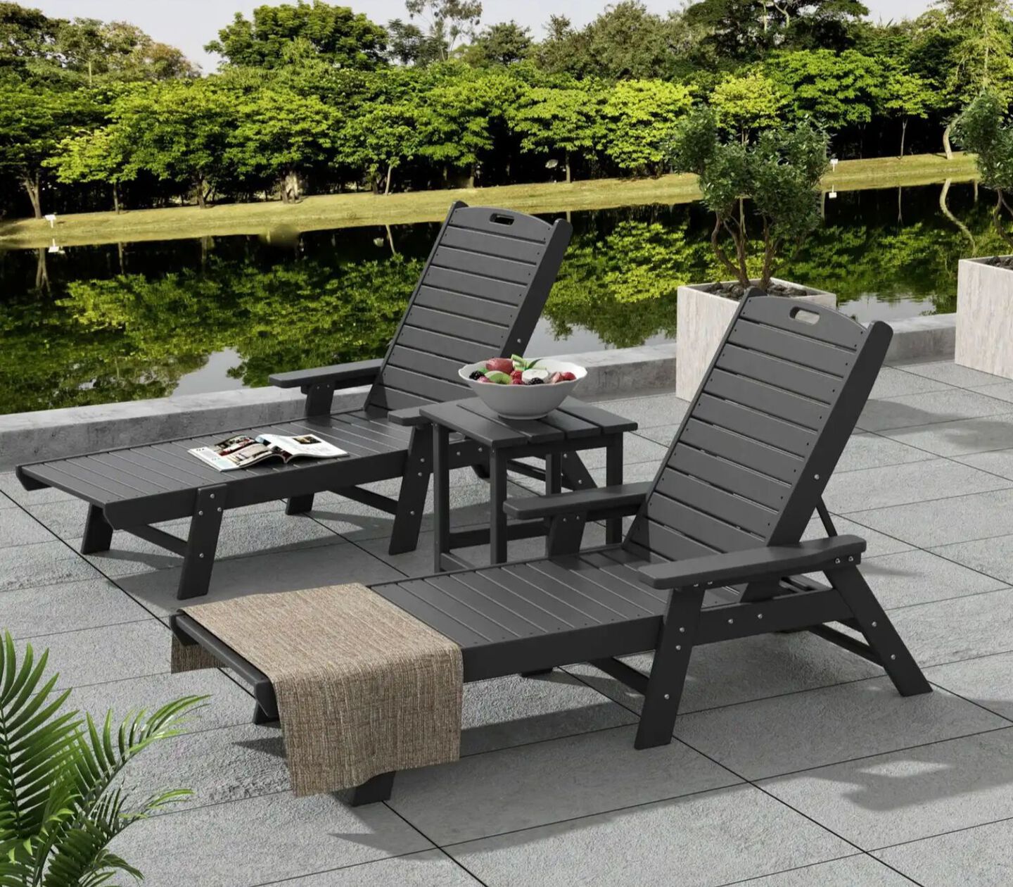 Two dark grey patio lounge chairs with matching table between them