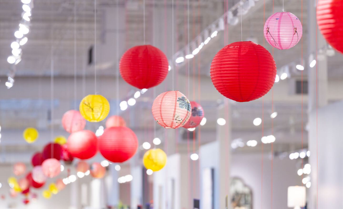 Red, pink, and yellow paper lanterns hanging from the ceiling in the Mathis Home store