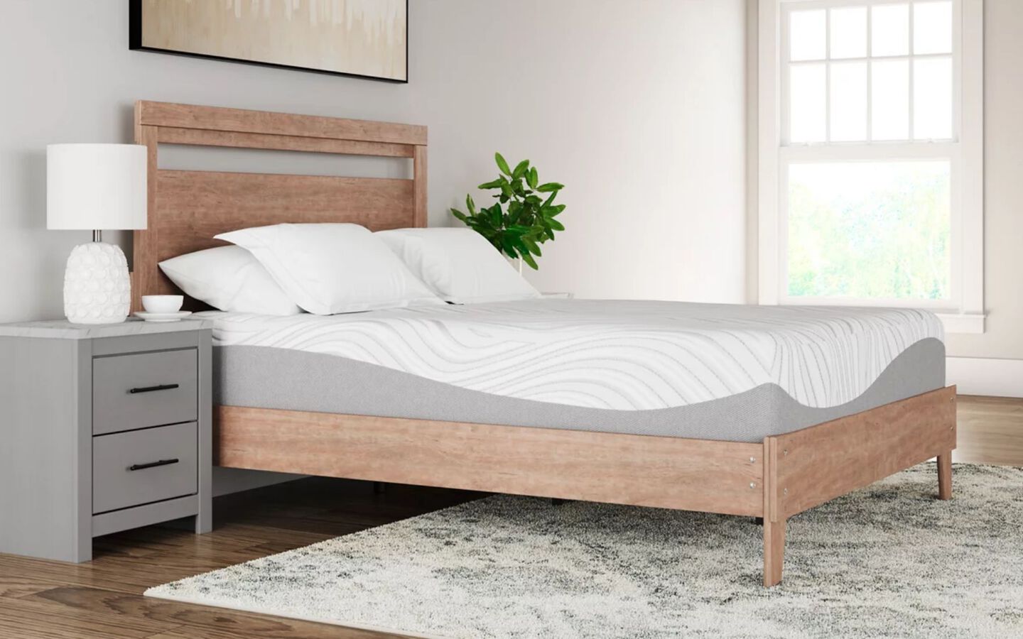 Light grey and white mattress on a wooden bedframe next to a grey nightstand