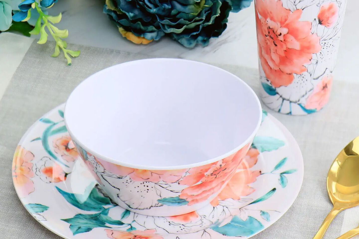 Closeup image of a floral peach, teal, and white tea cup and saucer
