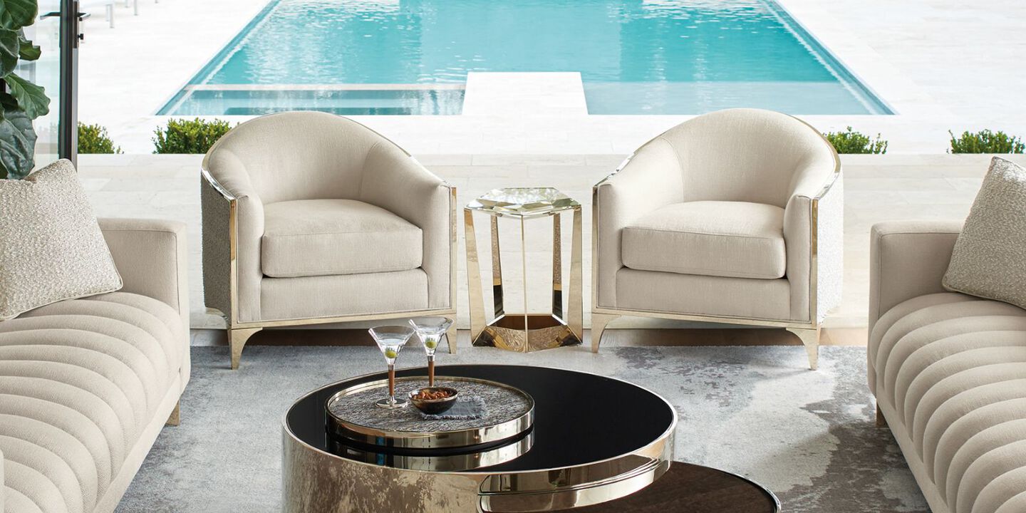 two light beige chairs surrounding a silver and glass gemstone shaped side table