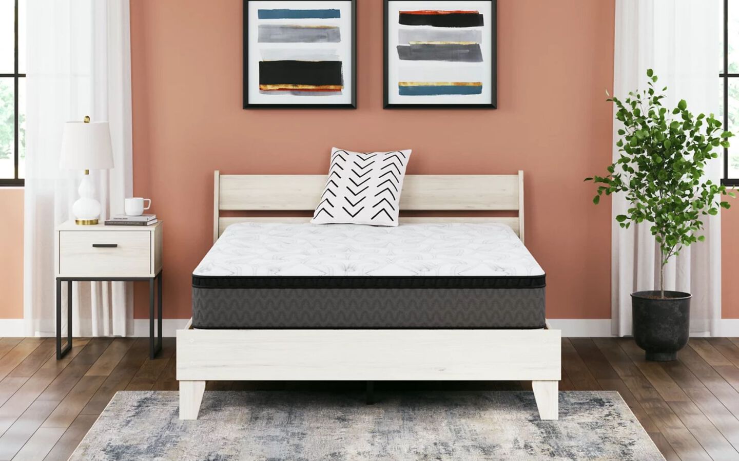 Grey and black mattress on a white bedframe in a bedroom