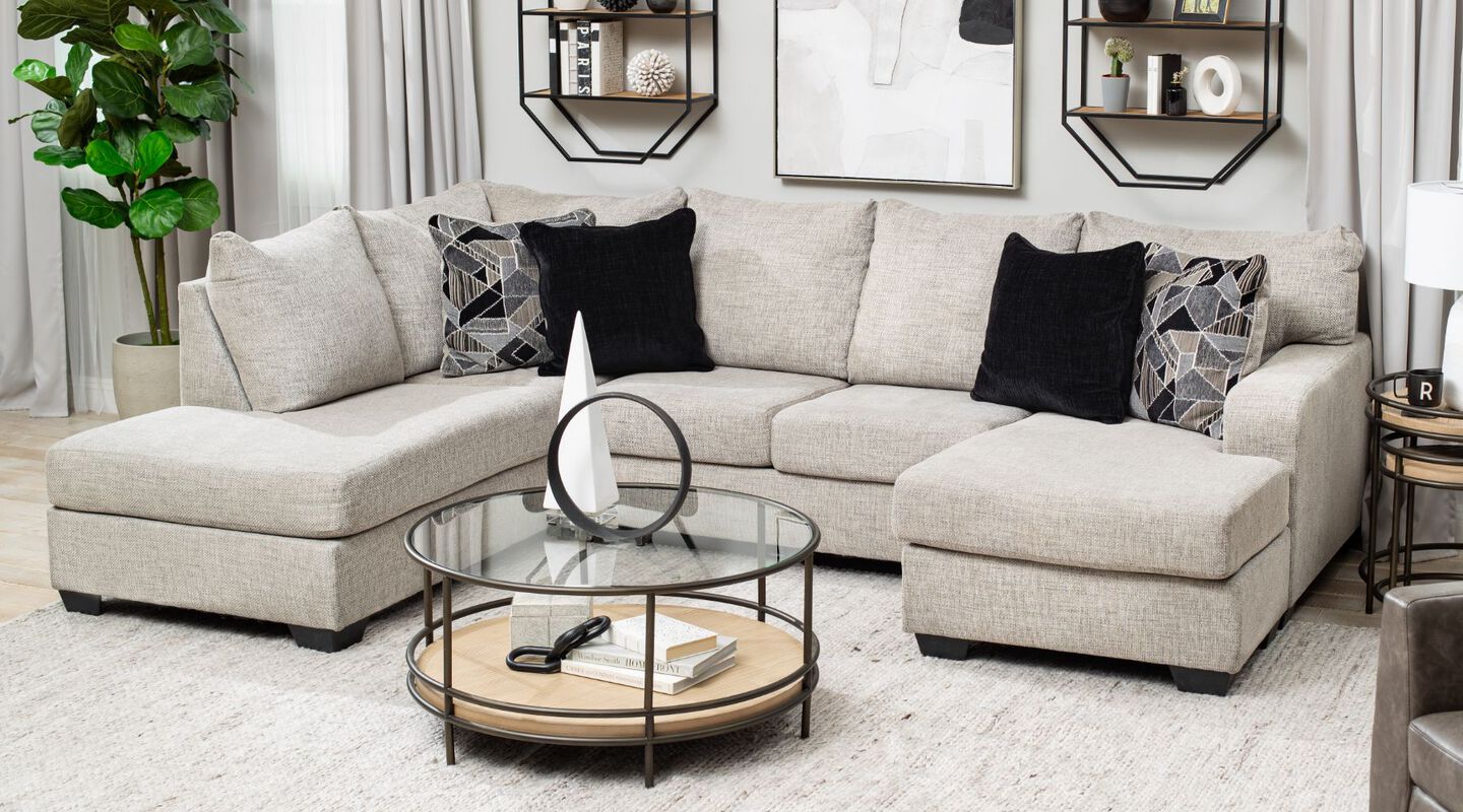 Living room with light beige couch and black and grey pillows, and glass coffee table