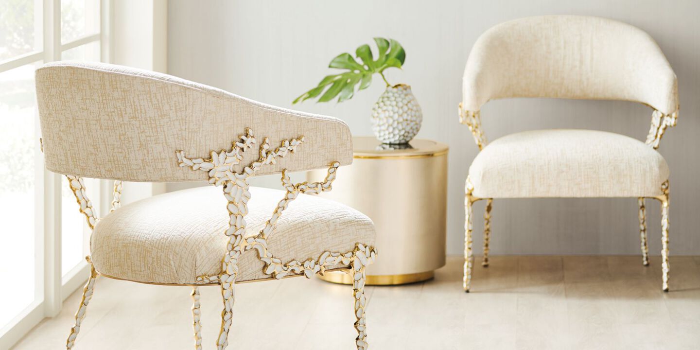 two light cream-colored chairs with gold and white detailing
