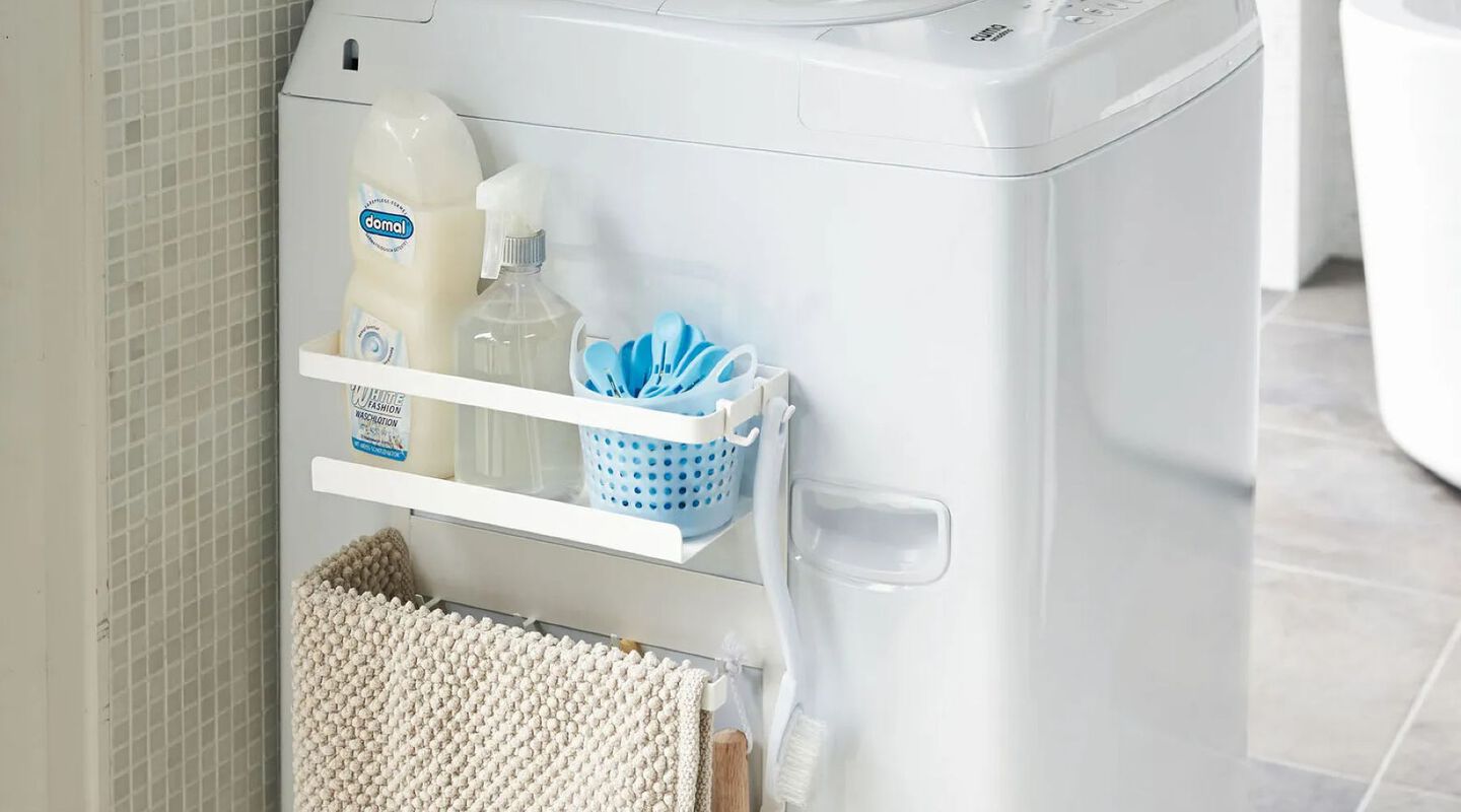 White shelf filled with cleaning supplies sitting next to a washing machine