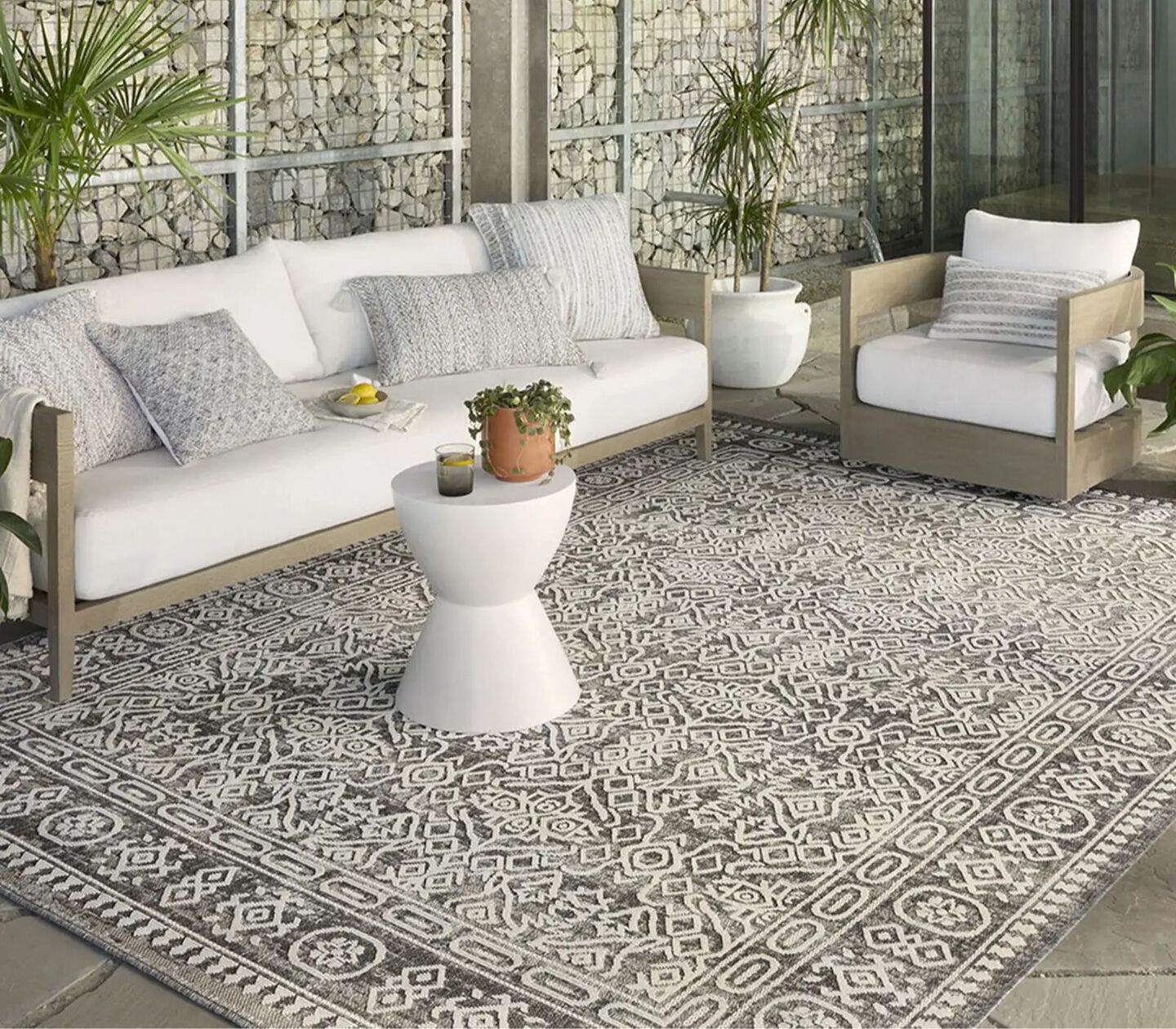 Beige and white outdoor patio sofa sitting on a grey and white rug