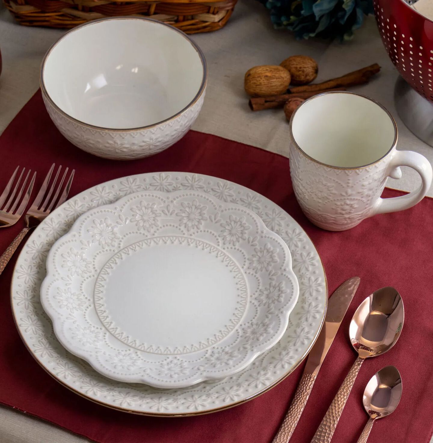 Place setting with white plates, bowl, matching cup, and bronze silverware sitting on a red placemat