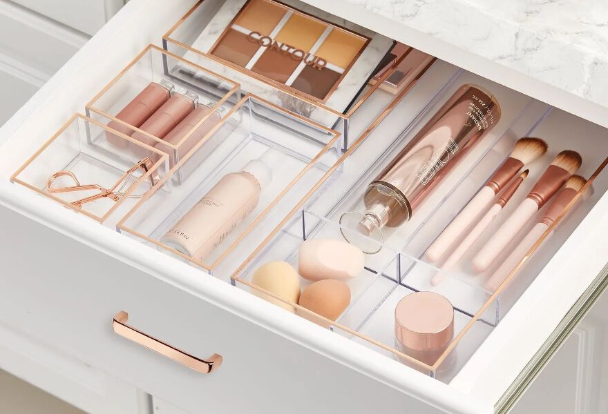 Open bathroom drawer with clear organizers inside filled with makeup