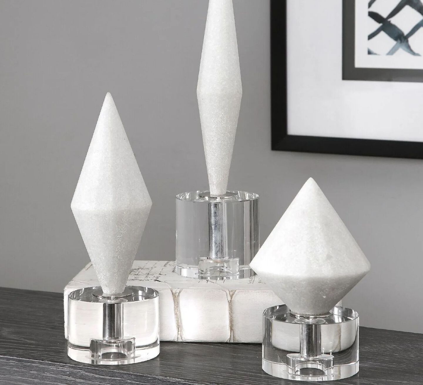 Three white stone sculptures sitting on top of glass bases