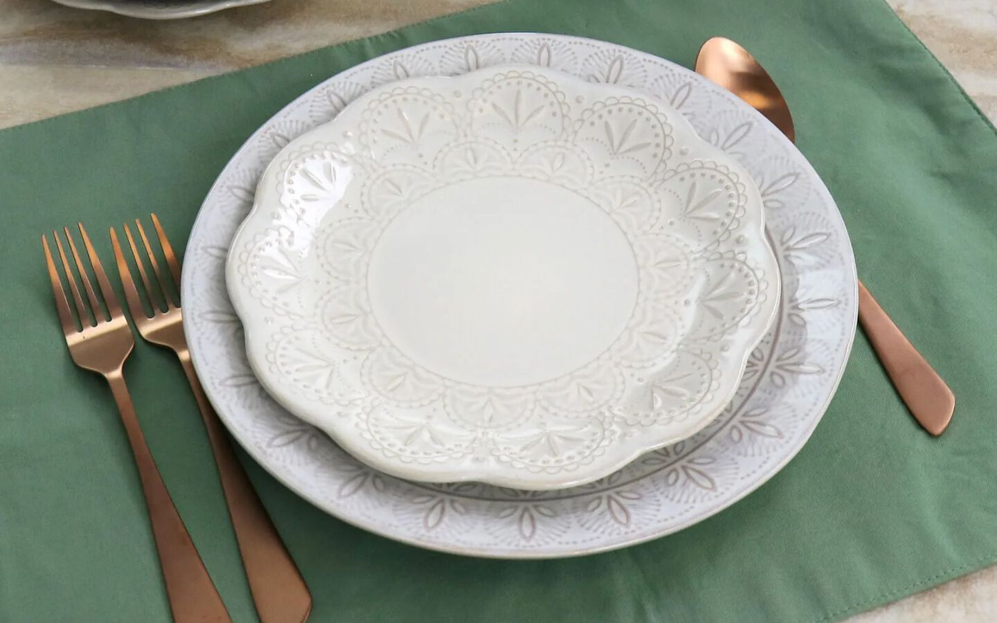 Place setting with white plates, bronze silverware, and green placemat