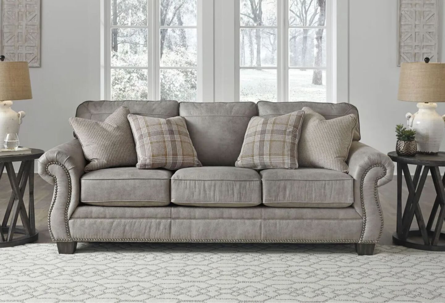 Living room with grey sofa with plaid and grey pillows and two matching side tables