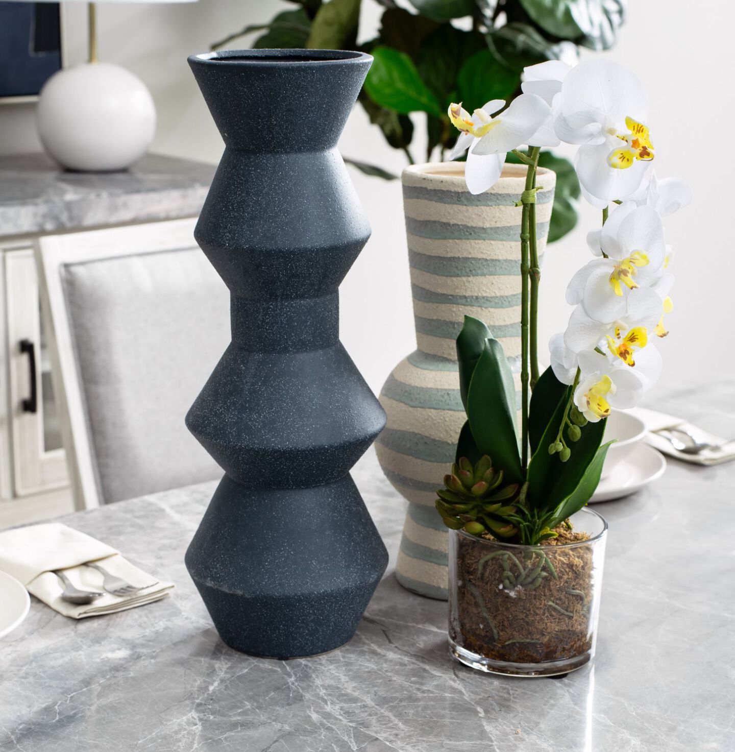 Grey marble counter with two vases and a potted faux plant