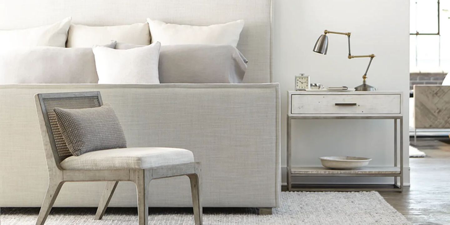 bedroom setting with grey wooden chair, light grey nightstand, and a bed with a grey headboard and white pillows