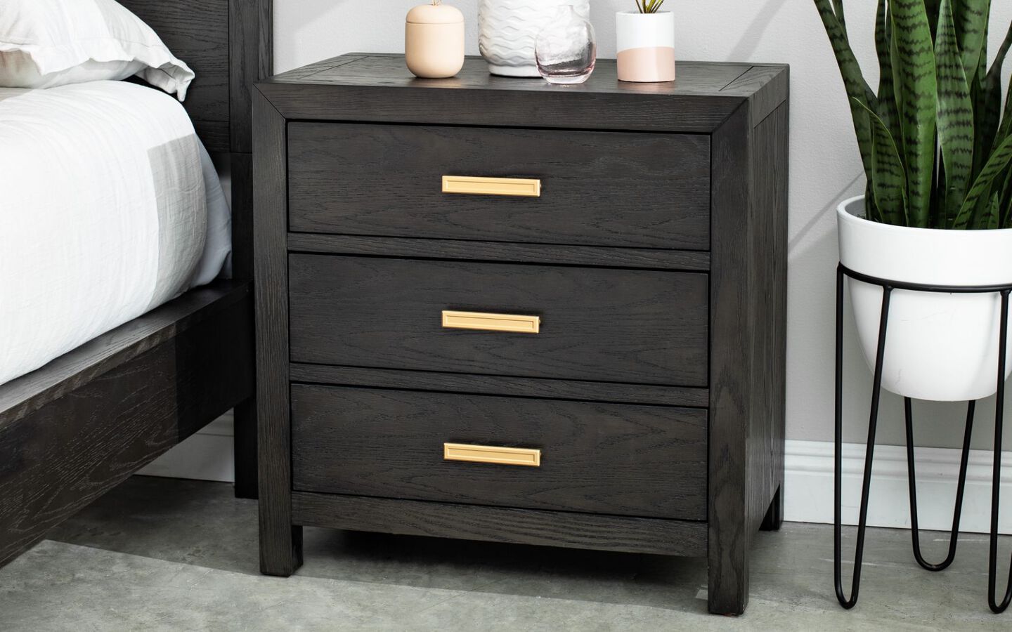 Black and gold wooden nightstand next to a potted plant
