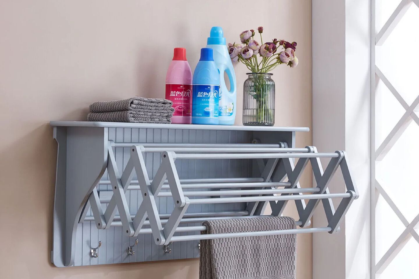 Grey wall shelf with cleaning supplies, towels, and a vase on top