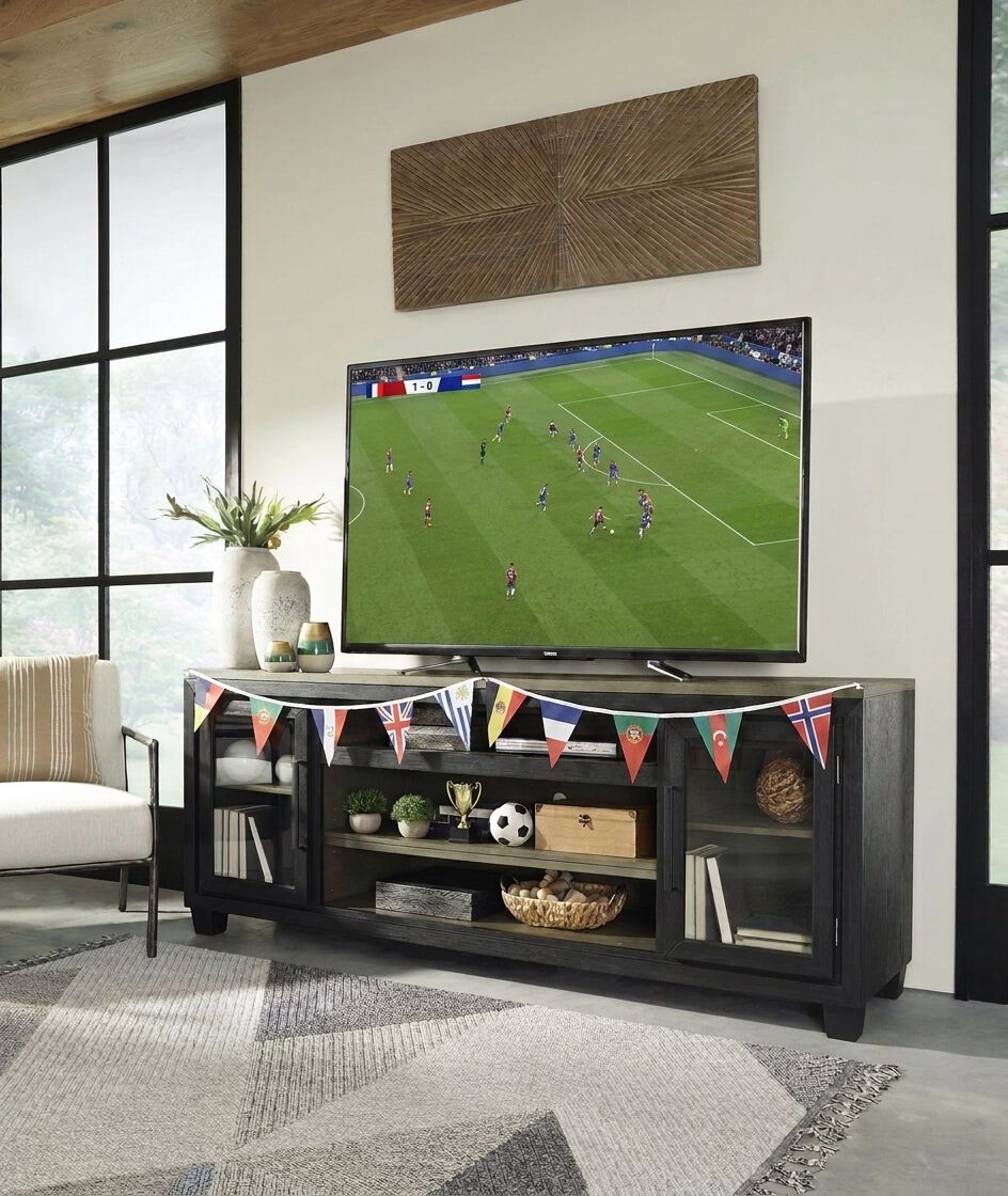 A large flatscreen TV showing a soccer game on a low-profile black media console.