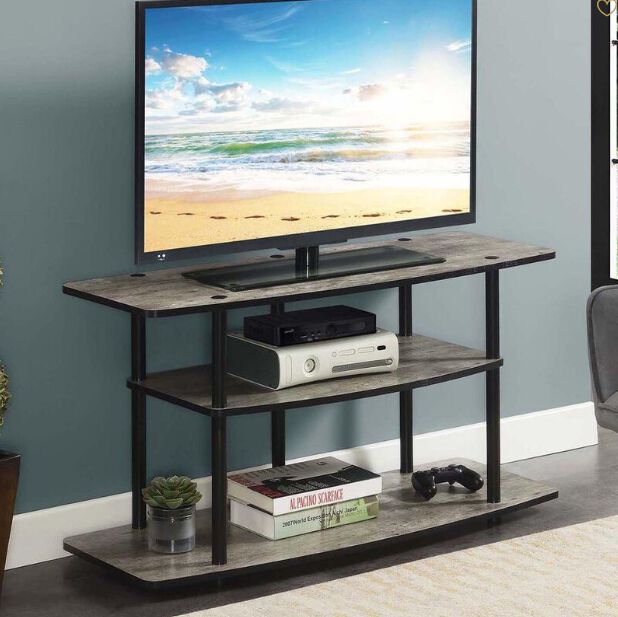 A basic three tiered TV stand with a gaming console, decorative items and a TV on the top tier. 