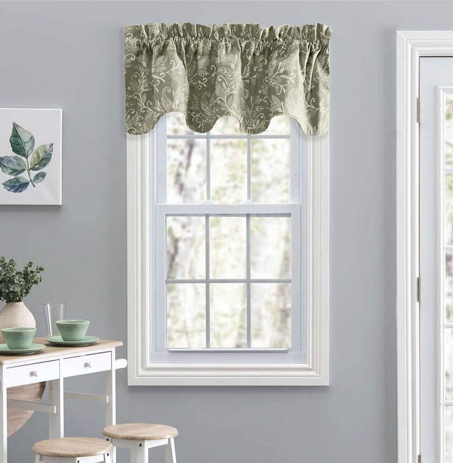 White paneled window with short green patterned curtains