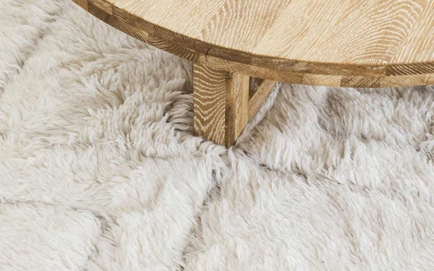 zoomed in image of a wooden table atop a white shag rug