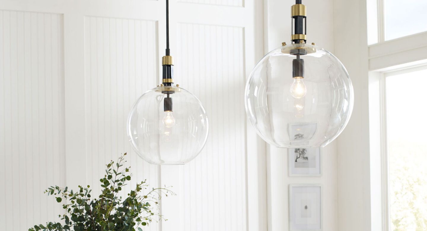Two clear light fixtures hanging in a white kitchen