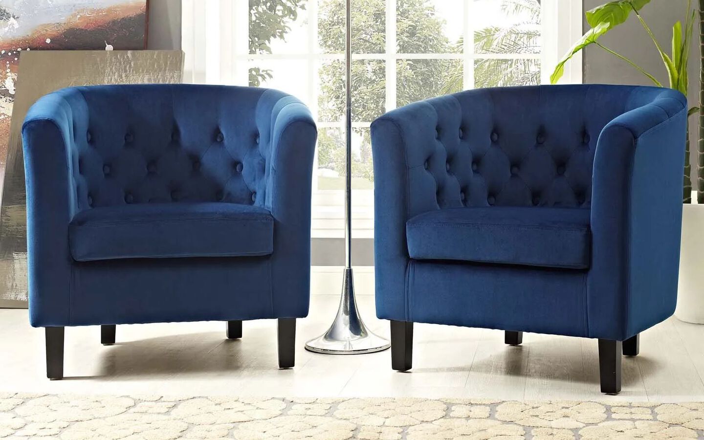 Two blue upholstered chairs sitting around a silver lamp